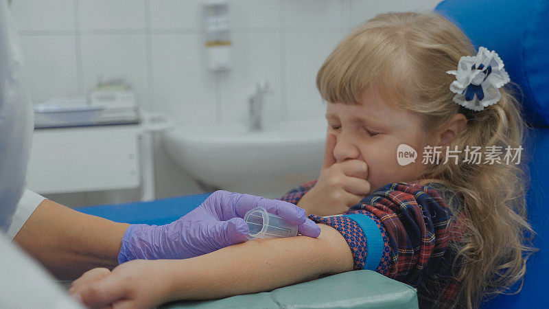 护士正在从一个小女孩手臂的静脉中提取血液样本