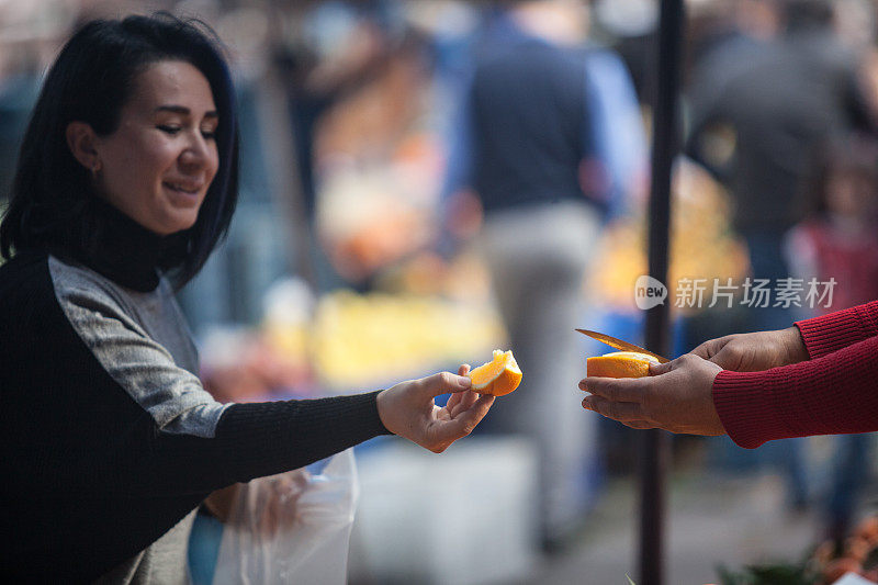 在农贸市场，卖家向买家提供橙子片