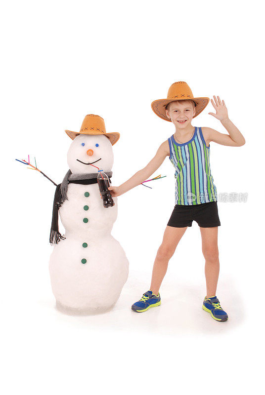 可爱的男孩拿着一个可乐瓶靠近一个雪人带着围巾和帽子