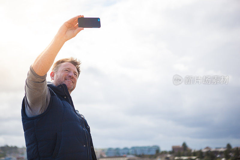 一个成熟的男人在下午海边散步时自拍