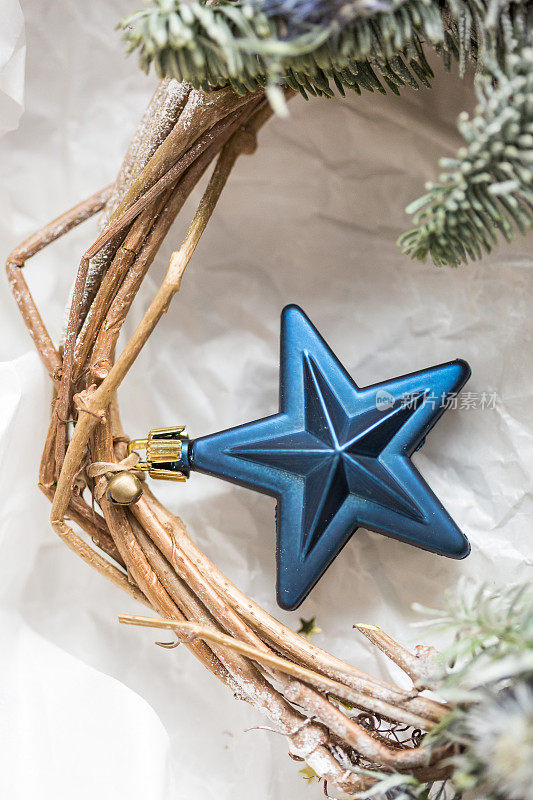 装饰，节日，新年概念。奇妙的蓝星，圣诞节的象征之一，它是用金色的细丝带和小铃铛绑在柔软的树枝上，彼此紧密地交织在一起