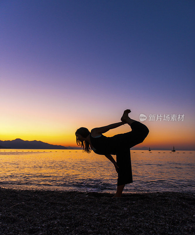 女子练习武士瑜伽姿势户外日落天空的背景