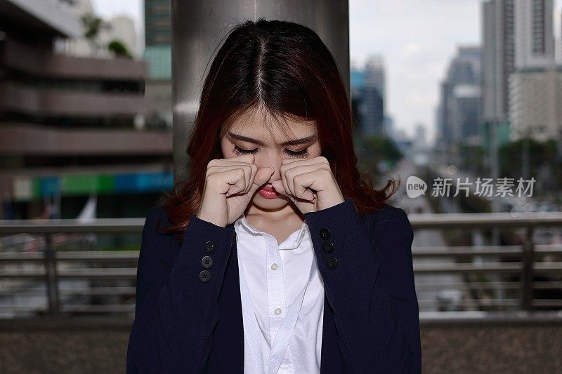 近距离观察失意压抑的年轻亚洲女商人在办公室外捂着脸哭泣。