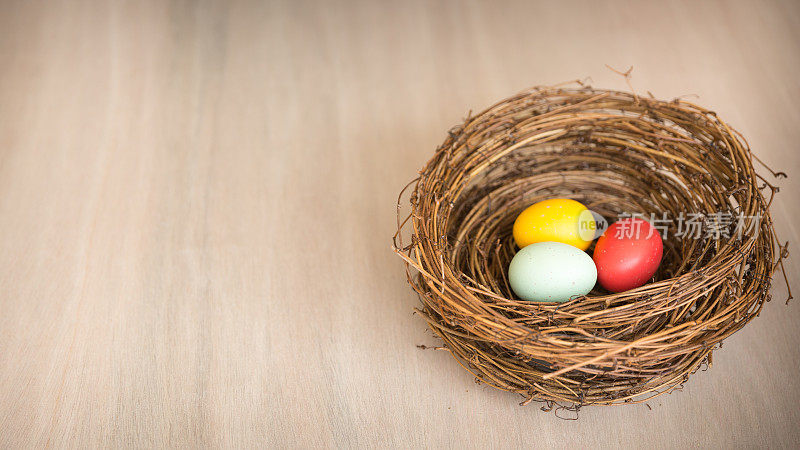 彩色的复活节彩蛋放在一个乡村的窝或木制的篮子里。