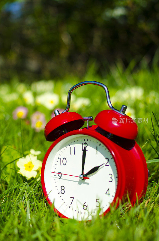 象征性的闹钟坐在花坛上，时间转换为夏令时