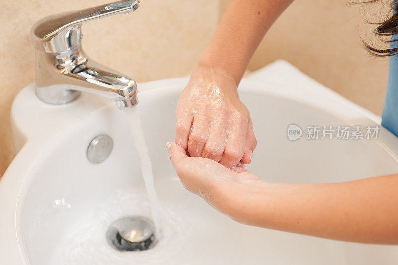 在浴室水槽里洗手的女人