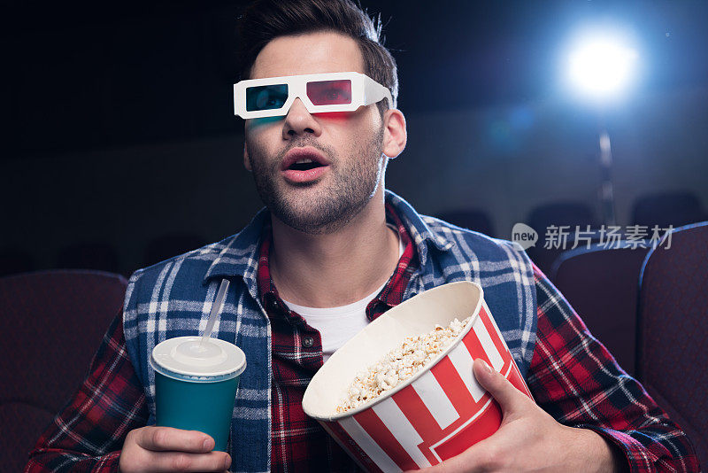 情绪英俊的3d眼镜，爆米花和苏打水在电影院看电影