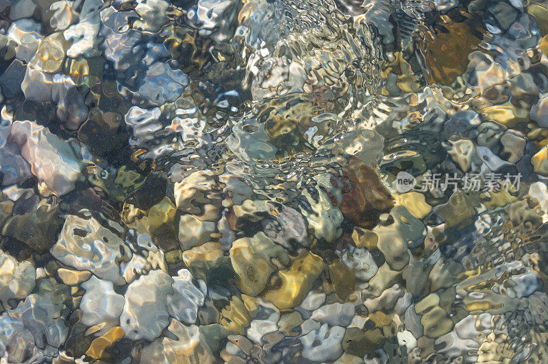 海卵石滩上有五颜六色的石头，浪花上有泡沫