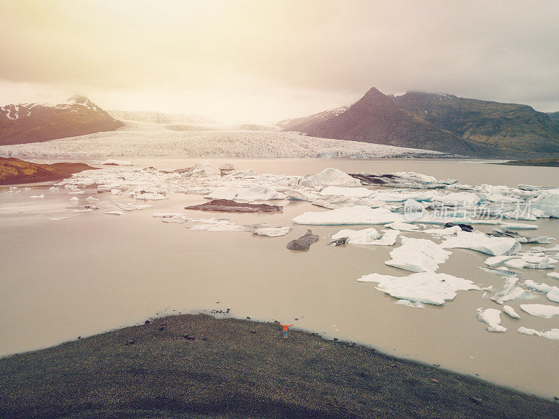 无人机航空壮观的冰川泻湖在冰岛与冰山漂浮在水上，阴天