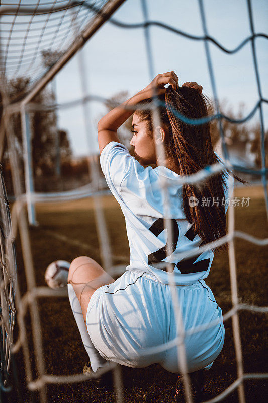 性感的女足球运动员在一个体育场摆姿势