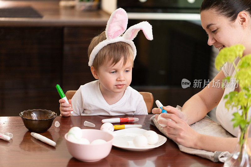 妈妈和孩子在为复活节画彩蛋。妈妈和蹒跚学步的男孩庆祝复活节