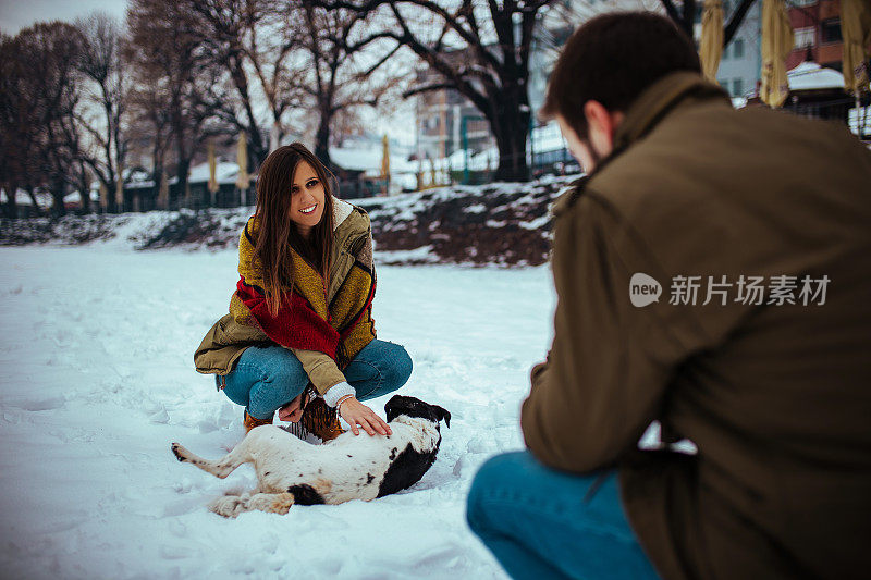 这对恩爱的夫妇享受着这一天。一个男人在河边拍他女朋友和一只狗的照片。