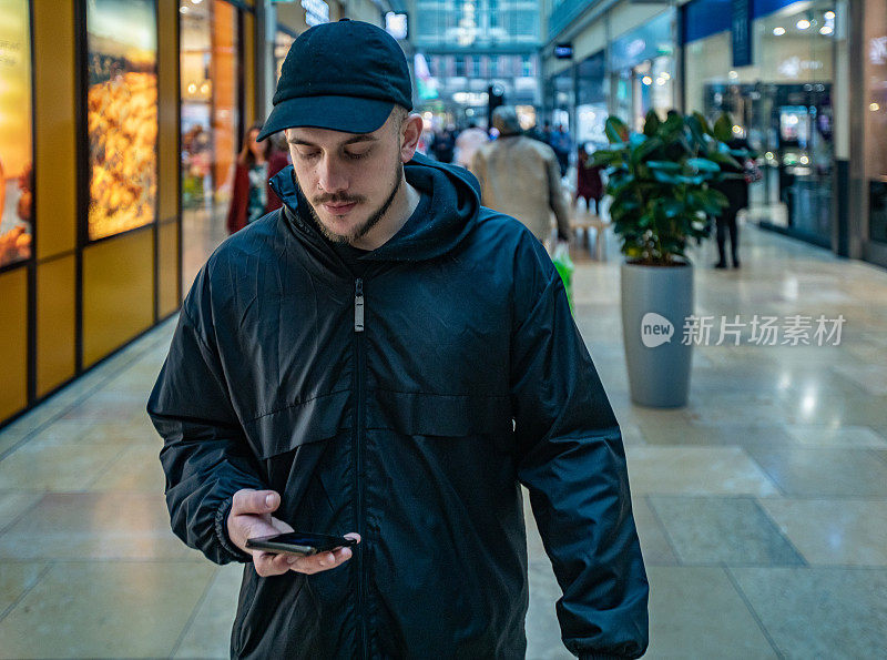 年轻的成年男子在购物中心里打电话