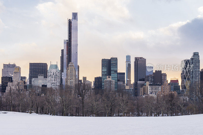 在美国纽约市曼哈顿市中心的冬天，从一个白雪覆盖的中央公园看到的城市景观。