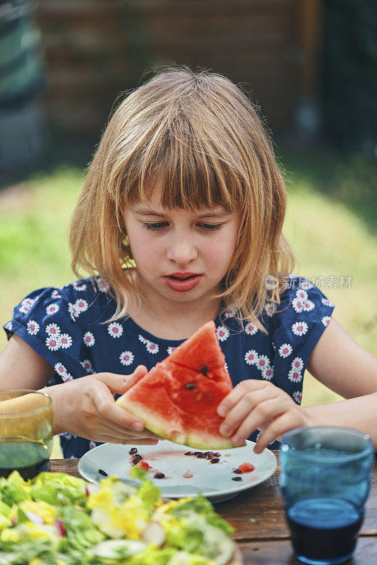 可爱的女孩在外面的花园里吃新鲜的西瓜