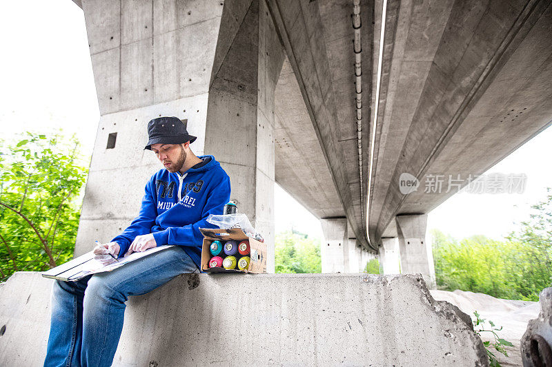 年轻的涂鸦艺术家在高速公路地下通道创作一个涂鸦之前做一个素描