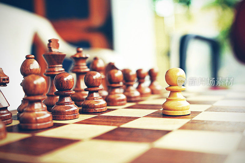 在一盘国际象棋中，一个白色的棋子面对着另一组黑褐色的棋子