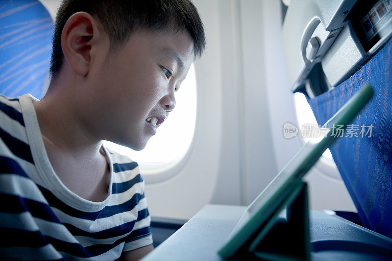 小男孩在飞机上用平板电脑学习