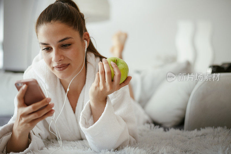 年轻漂亮的女人发短信上网在家里的沙发上。库存图片