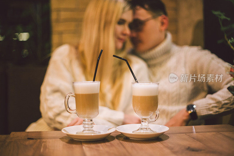 年轻幸福的情侣在咖啡馆相爱，男人和女人一起微笑拥抱，喝咖啡。一对夫妇在咖啡馆里聊天。一对幸福的夫妇在咖啡店享受咖啡。幸福,圣诞