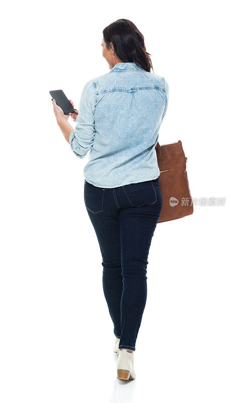 中年白人女性，穿着牛仔裤，拿着钱包，使用智能手机