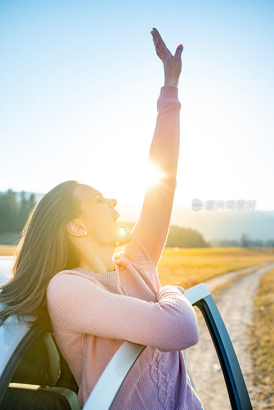 美丽的女人享受着日落时分的汽车之旅