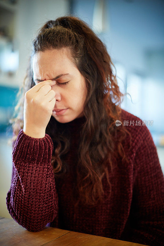 年轻的鬈发黑发女子看起来不高兴或痛苦，眼睛闭着