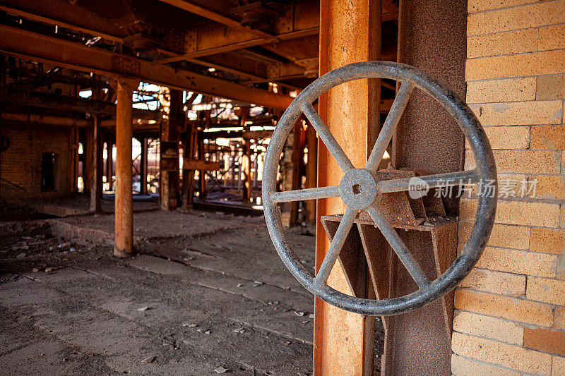 一个废弃铜厂墙上的大阀门轮，带有锈和砖的纹理