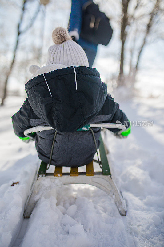 快乐的母亲和儿子在公园玩雪橇。