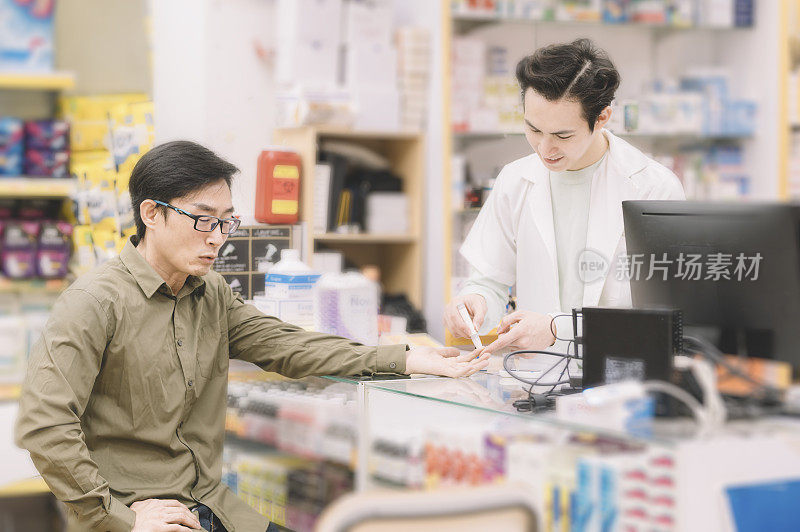 一名亚裔华人药剂师在药房为顾客进行血糖测试及糖尿病测试