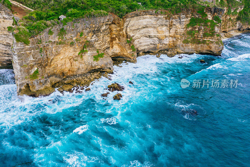 Uluwatu巴厘岛。蓝色的海洋和岩石山，覆盖着热带树木。