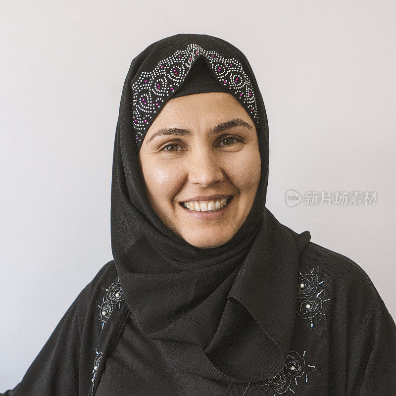 一个成熟的穆斯林妇女戴着头巾，对着镜头微笑的特写