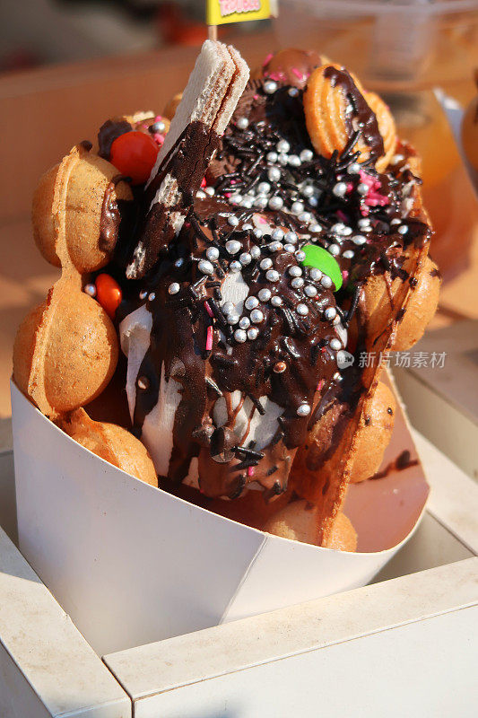 在糖果架上，气泡(蛋)华夫饼与冰淇淋，巧克力酱，饼干，糖果和撒在纸筒里的糖屑