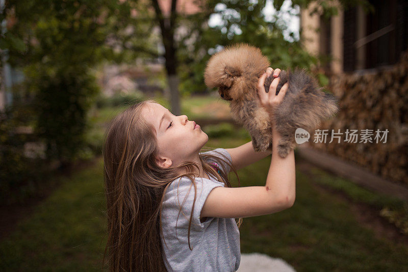 微笑的女孩在后院亲吻一只小狗