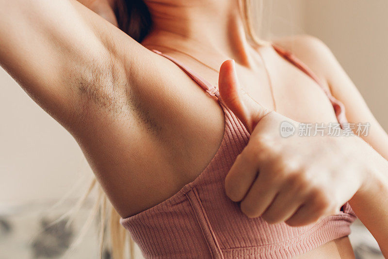 女性腋下毛发多且未刮胡子。身体积极的趋势。穿胸罩的女人举起手臂。接受身体的自然性
