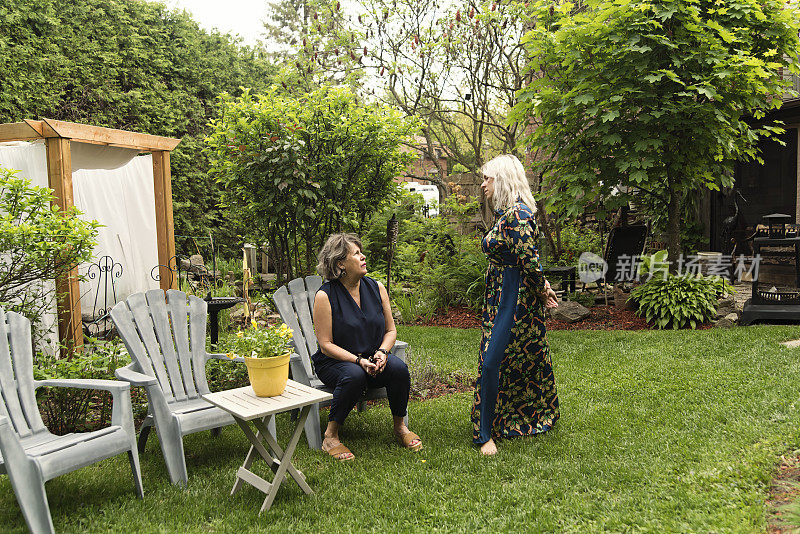 成年的女儿和年长的母亲在后院聊天。