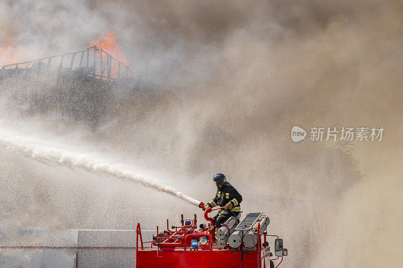 2020年8月5日俄罗斯秋明地区下涅瓦托夫斯克市。工业仓库失火。一名消防队员将一股水流引向着火的建筑物