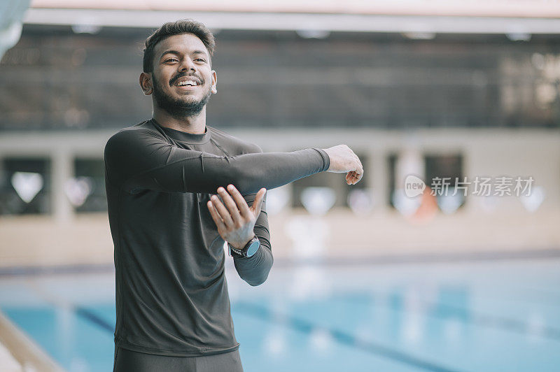 亚洲印度男子运动员游泳运动员微笑着看向公共游泳池热身运动