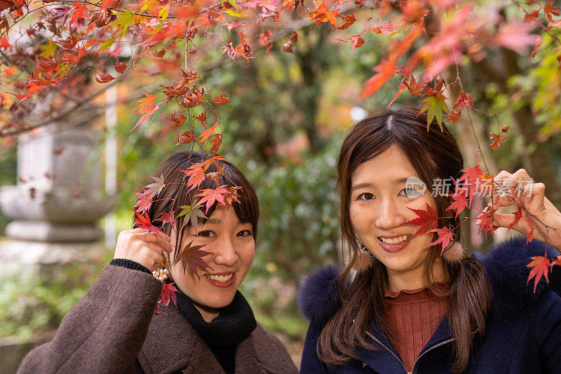 年轻女性朋友的肖像站在日本枫树下的秋天