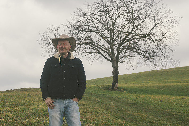 农夫戴着牛仔帽在早春的草地上