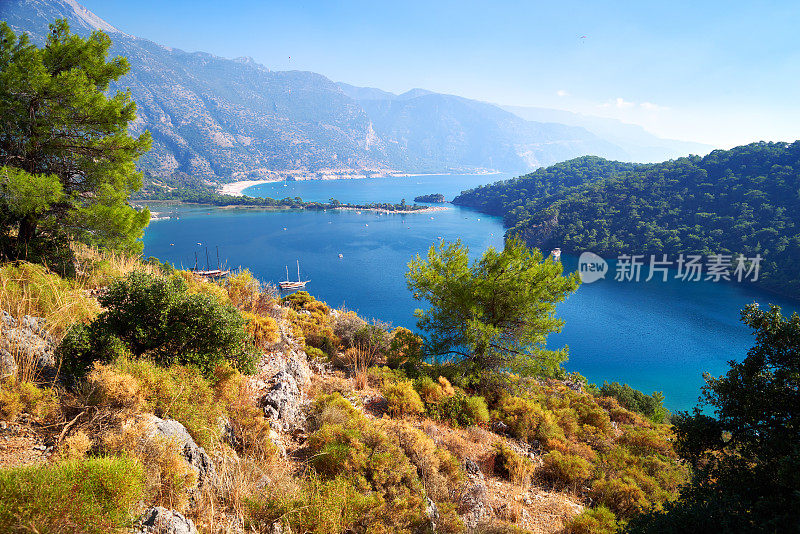 从山上看到土耳其Fethiye附近的Oludeniz泻湖的蓝色水面。地中海沿岸树木丛生，天空晴朗