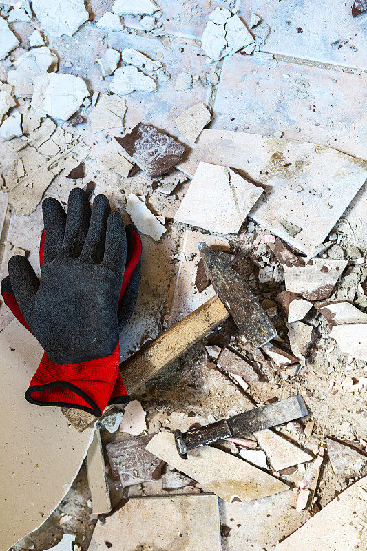 防护工作手套和锤子在破碎的瓷砖