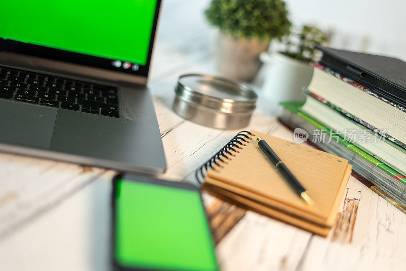 家庭办公室设置笔记本电脑与绿屏智能手机与绿屏笔记本和笔都在白色桌子上横微距拍照