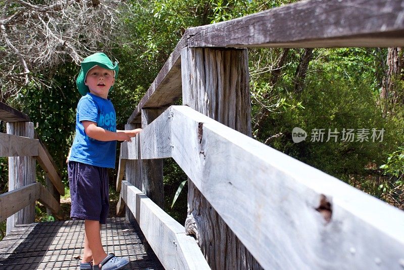 小男孩在大自然中俯瞰一座木桥