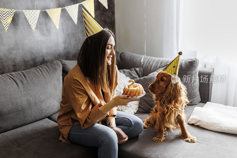 微笑的女人和她的狗在家里庆祝她的狗生日。