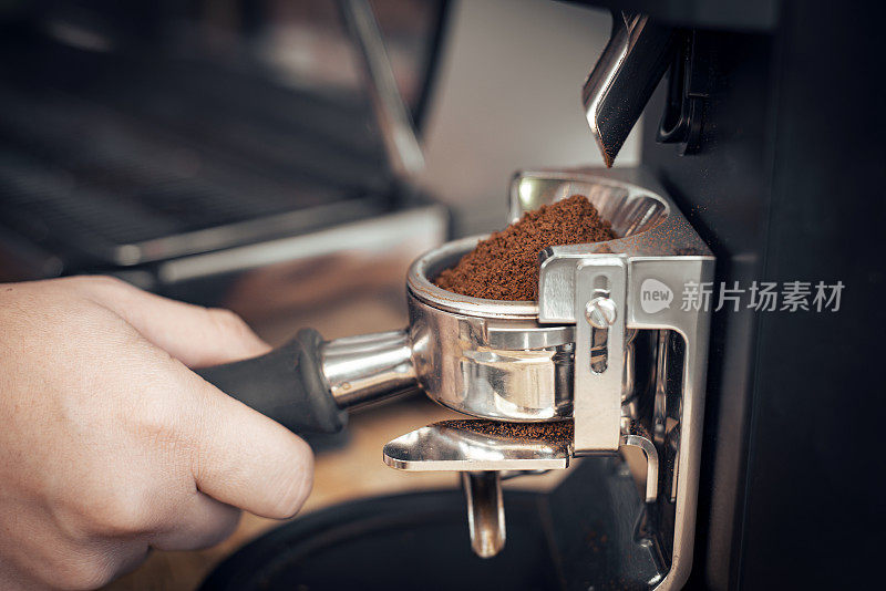咖啡师拿着浓缩咖啡机的折叠式过滤器。现磨的咖啡颗粒倒入浓缩咖啡机的滤纸中