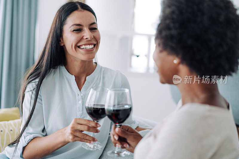 两个年轻的女人在家里放松的时候喝酒。