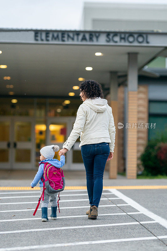 妈妈把蹒跚学步的女儿送到学校