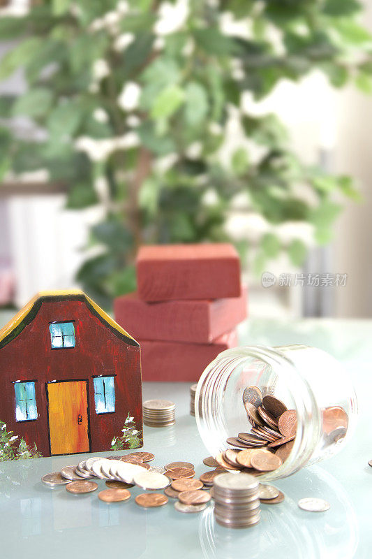 新屋建筑。漆过的木块构成了一所房子。装着硬币的玻璃罐可以用来买房子。