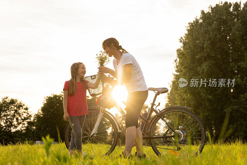 女儿在一次骑自行车旅行中休息时，在田里犁了花，然后在黄昏时分把花交给了她的母亲